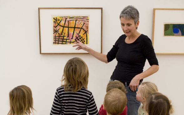 A woman explaining a picture to a group of children