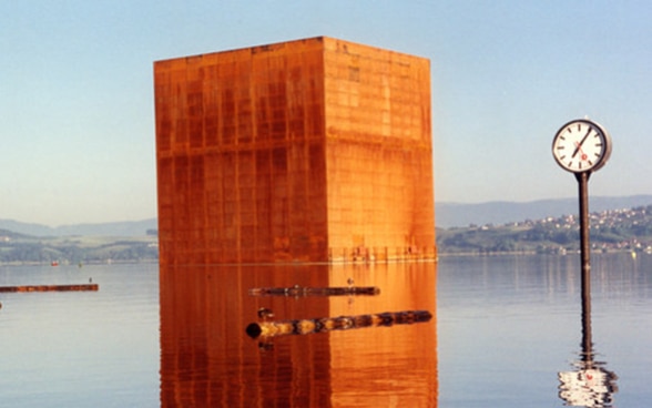 A monolith of rusted metal on the surface of Lake Murten.