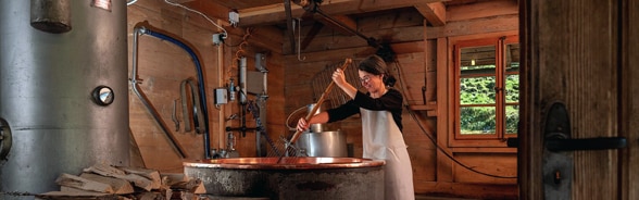 Woman making cheese with a traditional cheese vat