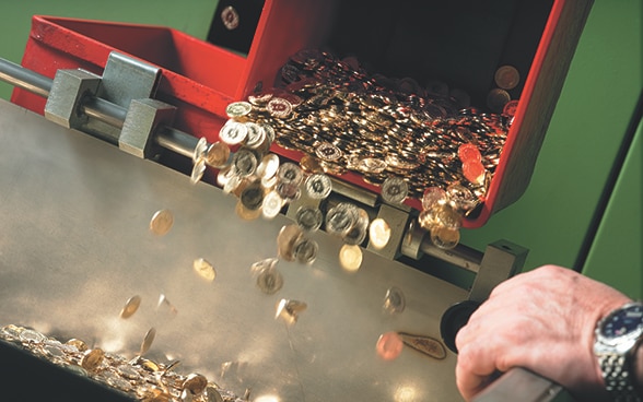 Monedas suizas salen de una acuñadora.