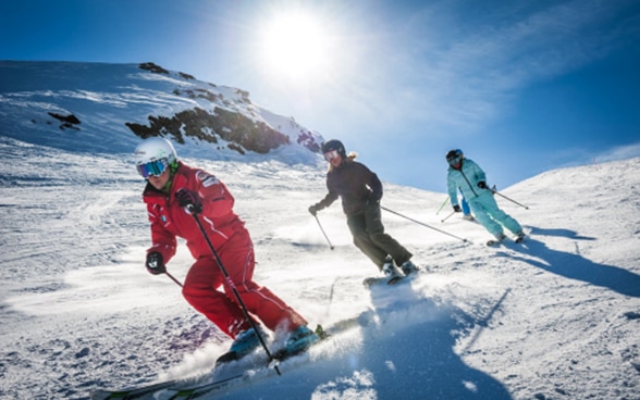 Trois skieurs descendant une piste de ski dans la région de la Jungfrau, dans l’Oberland bernois.