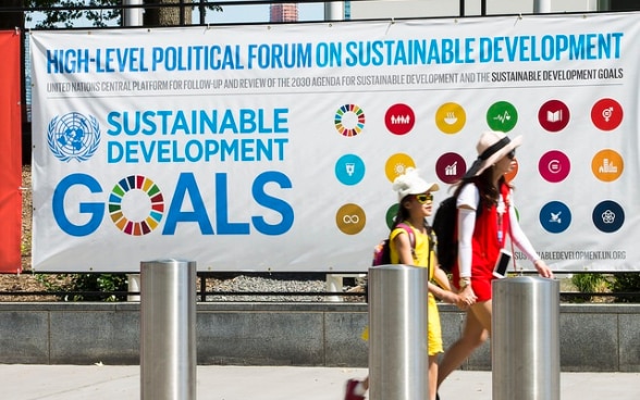 Tourists walking in front of a poster advertising the High-level Political Forum.