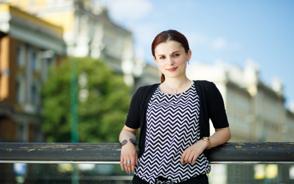 A young woman leaning against a railing.