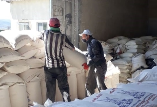 two men are stockpiling sacks