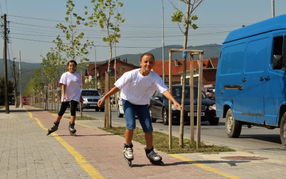 Zwei Jugendliche sind mit Rollerskates auf einem Fahrradweg unterwegs.