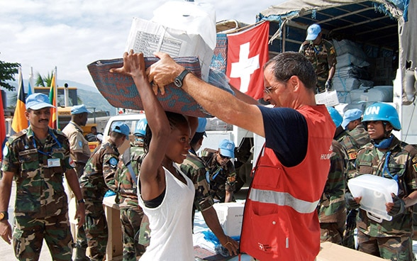 A member of the Swiss Humanitarian Aid Unit (SHA) distributes relief supplies.