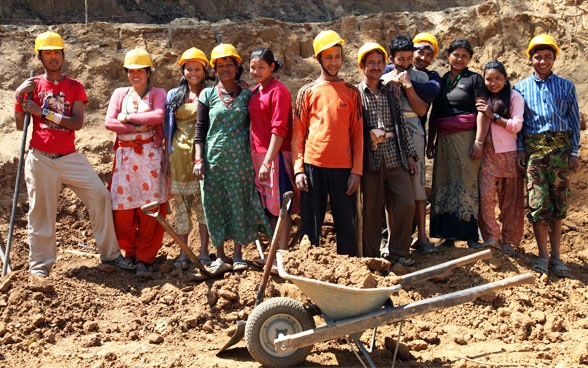 Una dozzina di Nepalesi al lavoro, con caschi da cantiere.