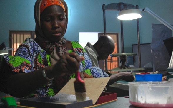 Una mujer maliense confecciona una caja de conservación.