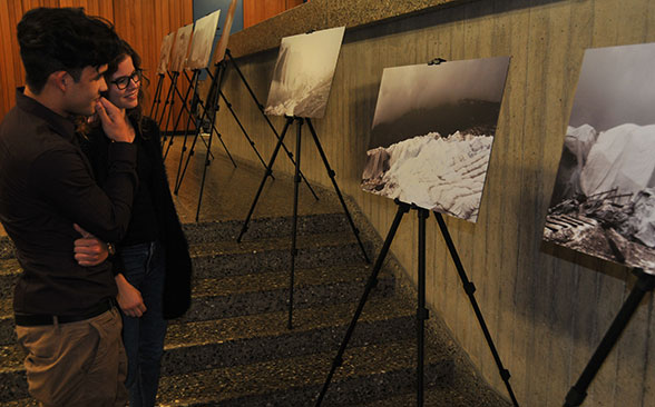 Eine Schülerin und ein Schüler stehen vor Schwarz-Weiss-Fotos und betrachten sie.