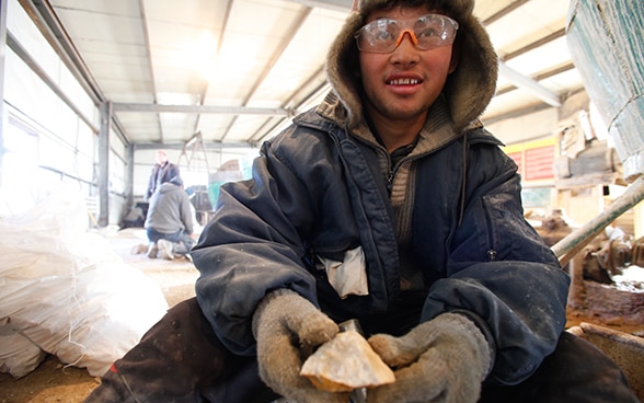 A young miner holding out mined gold ore.
