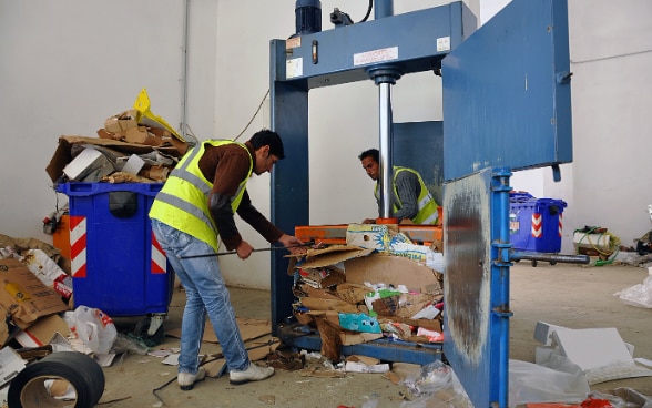 Zwei Personen kümmern sich im Recyclingzentrum einer albanischen Gemeinde um Papier- und Kartonabfälle.