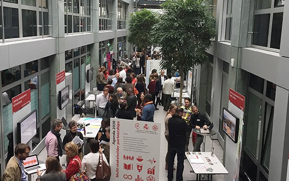 Visitatori della Fiera della ricerca discutono e passeggiano tra gli stand.