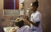 Samrawit, una giovane eritrea, è stata fotografata sul posto di lavoro, in una residenza per anziani in Vallese, mentre spazzola i capelli a una signora.