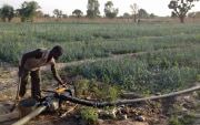 Ein senegalesischer Bauer nimmt eine Motorpumpe in Betrieb.