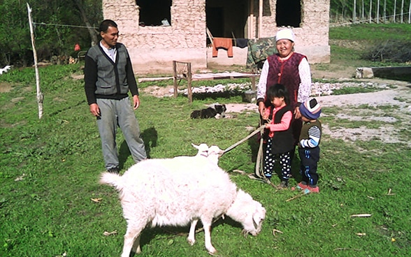 Nurdinov Jeenbek et sa famille posent en compagnie de leur chèvre laitière, qu’ils ont reçue dans le cadre du projet NMA.