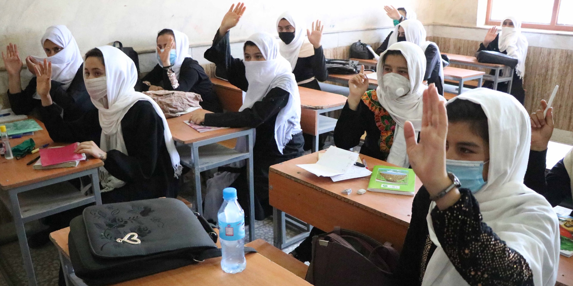  Une salle de classe en Afghanistan avec des écolières qui lèvent la main pour répondre.