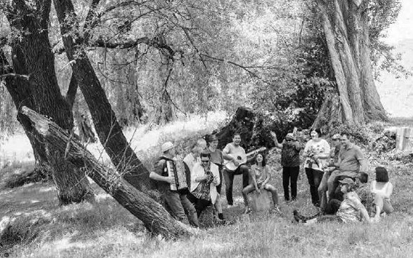 A group playing music together in a forest glade.