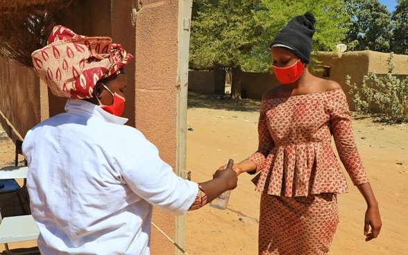 Two African women wear masks and disinfect their hands due to COVID-19.