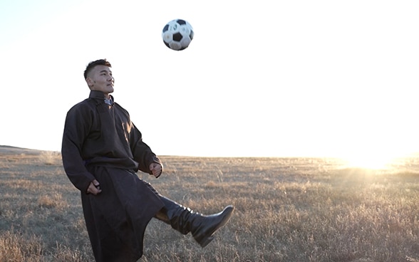 Un uomo calcia un pallone. Sullo sfondo, la steppa mongola.
