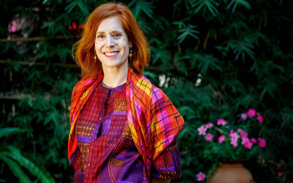 Nathalie Chuard wearing a colourful dress and smiling at the camera.