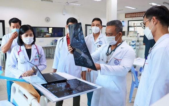 Morning rounds at a Kantha Bopha children's hospital. A doctor looks at a patient's X-ray. 