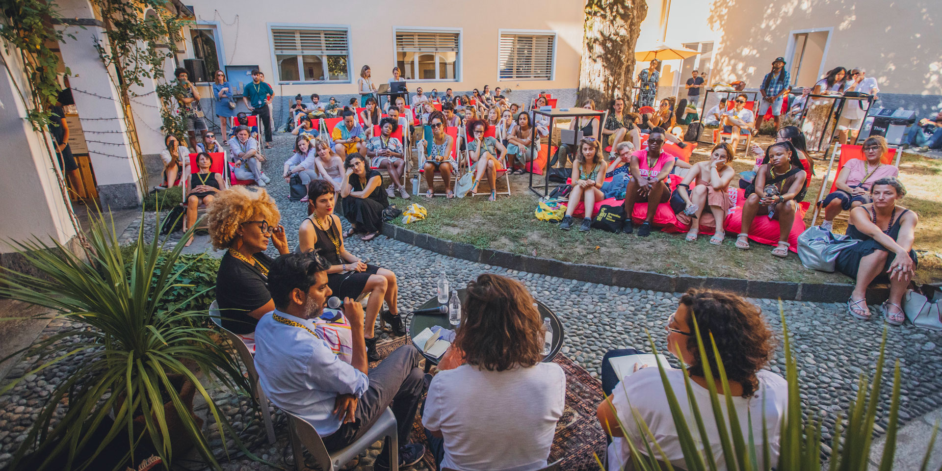 Varios directores celebran una conferencia al aire libre ante un numeroso público.