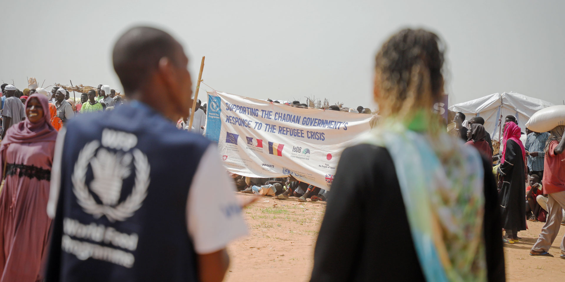 La directrice de la DDC, Patricia Danzi, et un représentant du PAM se tiennent devant le camp de réfugiés à Adré au Tchad, à la frontière avec le Soudan.