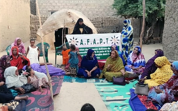 Un groupe de femmes sont assises en cercle et en tailleur sur le sol et échangent entre elles