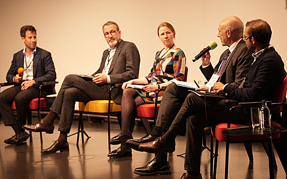One woman and four men sitting on stage for a panel discussion.