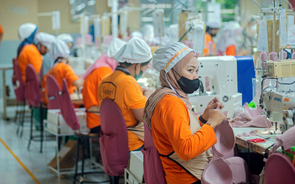 Eine indonesische Näharbeiterin mit Covid-Maske in einer modernen Produktionsstätte.