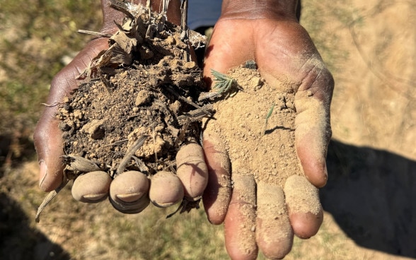 Dos manos extendidas con tierra húmeda en la derecha y tierra seca en la izquierda.