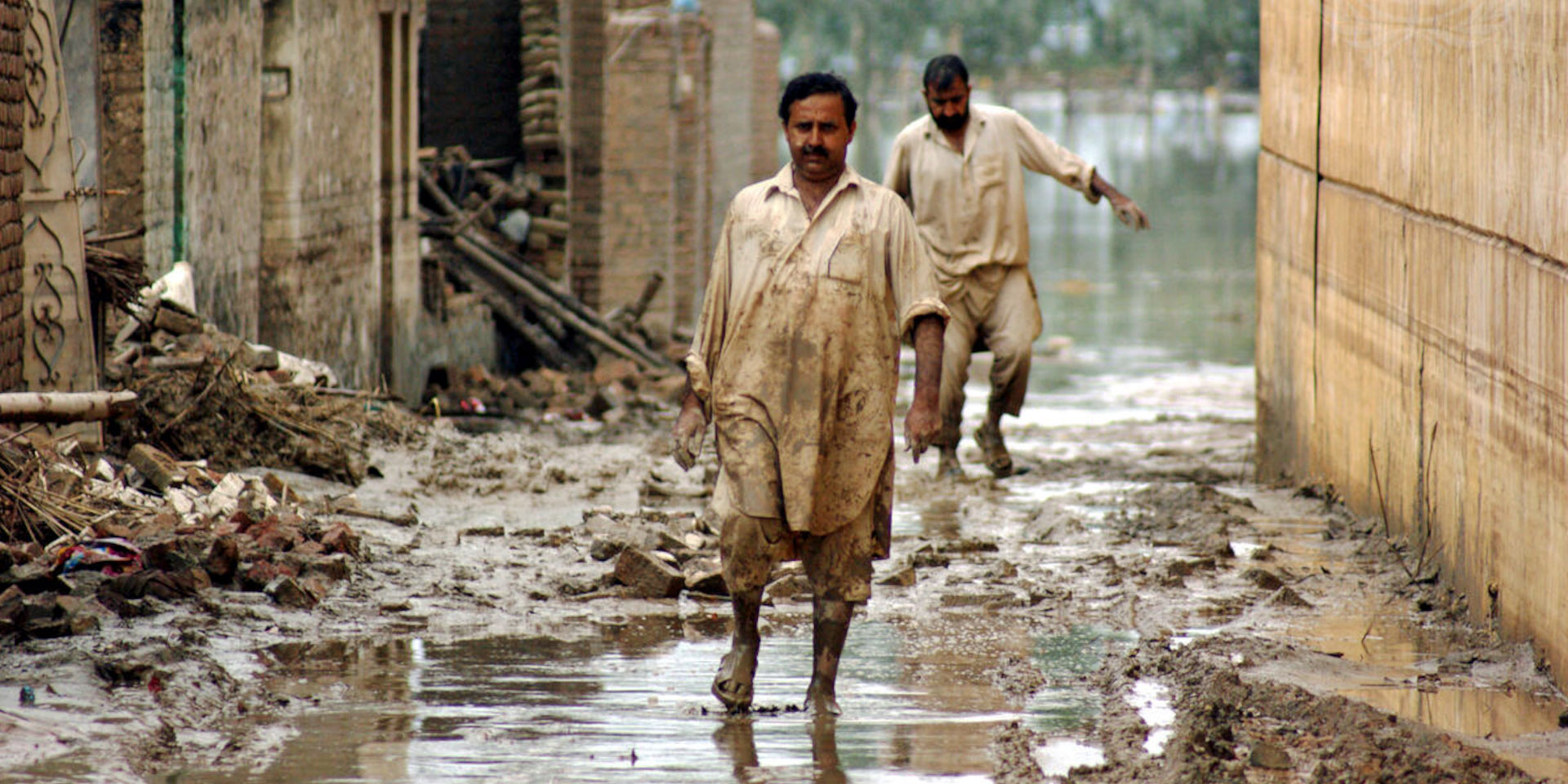 Des victimes des inondations de 2010 au Pakistan marchent dans les rues inondées de la ville de Nowshera, dans le nord-ouest du pays.