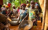 Des femmes, des hommes et des enfants d'un village de Sierra Leone, debout dans l'eau dans une mine d'or, essayant de libérer l'or volé des impuretés.