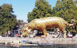 Ein grosser, aufgeblasener Plastikjaguar steht am Wasserrand auf der Île de Rousseau in Genf.