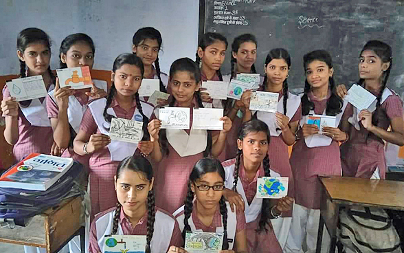 Des fillettes d’une école en Inde exhibent fièrement les cartes qu’elles ont dessinées et écrites à la main et qui contribueront, sur le Jungfraujoch, à l’établissement du record Guinness de la plus grande mosaïque de cartes postales jamais réalisée.