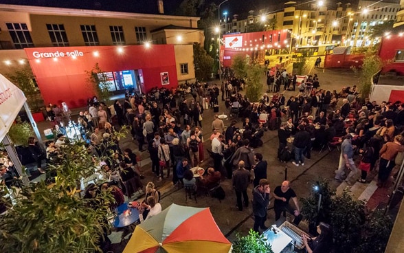 La imagen muestra el ambiente nocturno del festival: cinéfilos y especialistas del documental se reúnen y conversan en el recinto del festival.