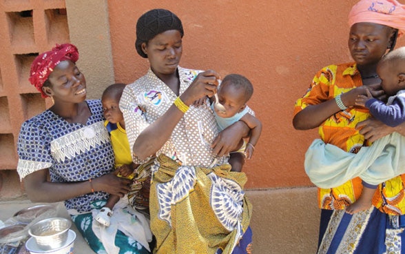 The photo shows three women each holding a baby. Two women feeding their babies. 