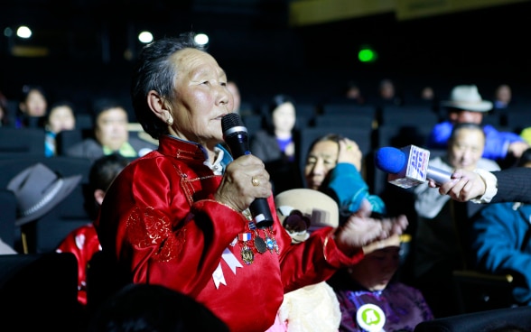 A woman from the audience speaks into a microphone. 