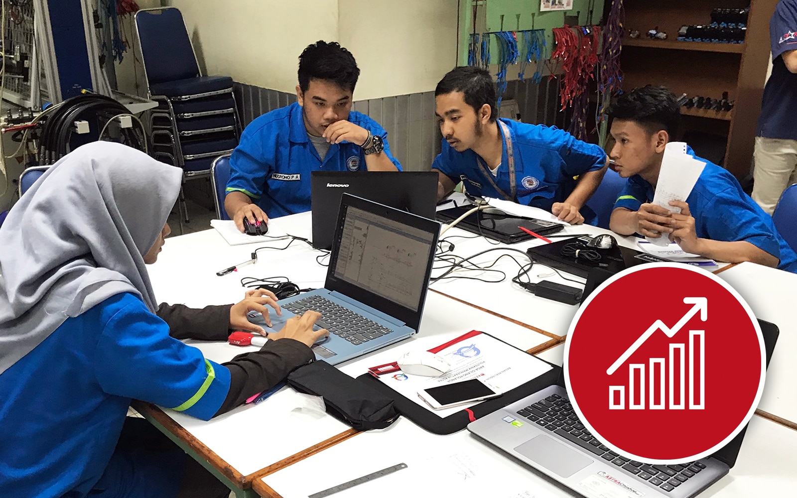  A woman and three men, all dressed in blue uniforms, working at computers.