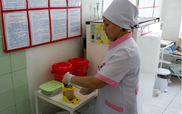 Die Pflegefachfrau Zulfia Djumaeva zerstört eine gebrauchte Spritze mit einer Nadelfräse. © DEZA