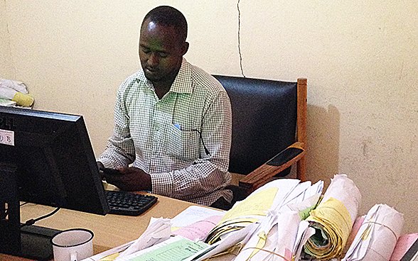 Assis à son bureau, un employé communal de la municipalité de Hargeisa entre les données de factures payées dans un système informatique.