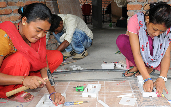 Due donne nepalesi al lavoro su un modello elettronico.