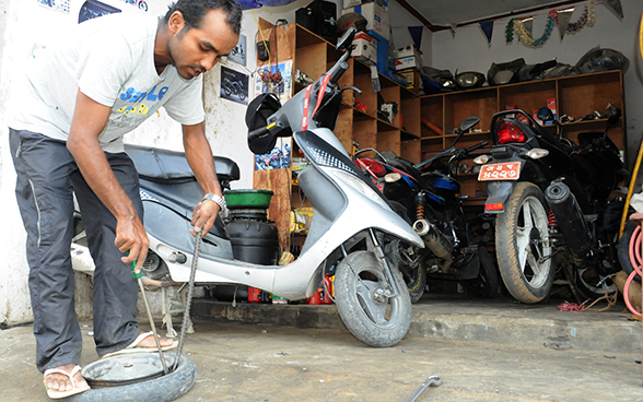 A young man changes a Vespa tyre. 