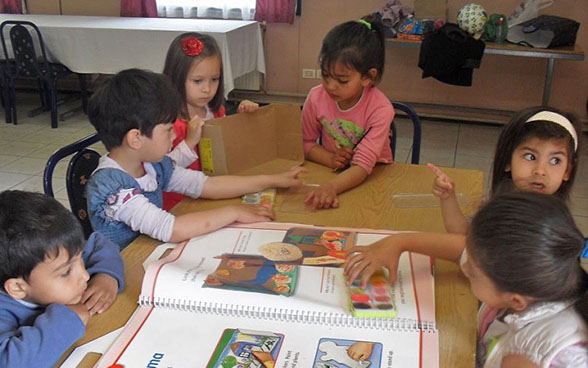 A group of Roma children in a classroom taking part in arts and crafts.