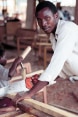 A young man sawing a wooden board.
