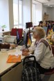 Employees sitting at a row of workstations each talking to a client.   