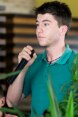 Ein junger Herr hält ein Mikrofon in der Hand und hört der Diskussion gebannt zu.