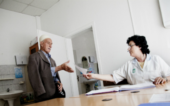 Eine Krankenschwester überreicht einem Patienten in einem Zentrum der primären Gesundheitsversorgung ein Rezept.