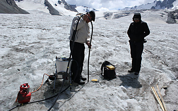 Dos hombres trabajando en un glaciar con sus equipos.