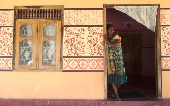 Eine sri-lankische Frau steht im Türrahmen ihres Hauses.